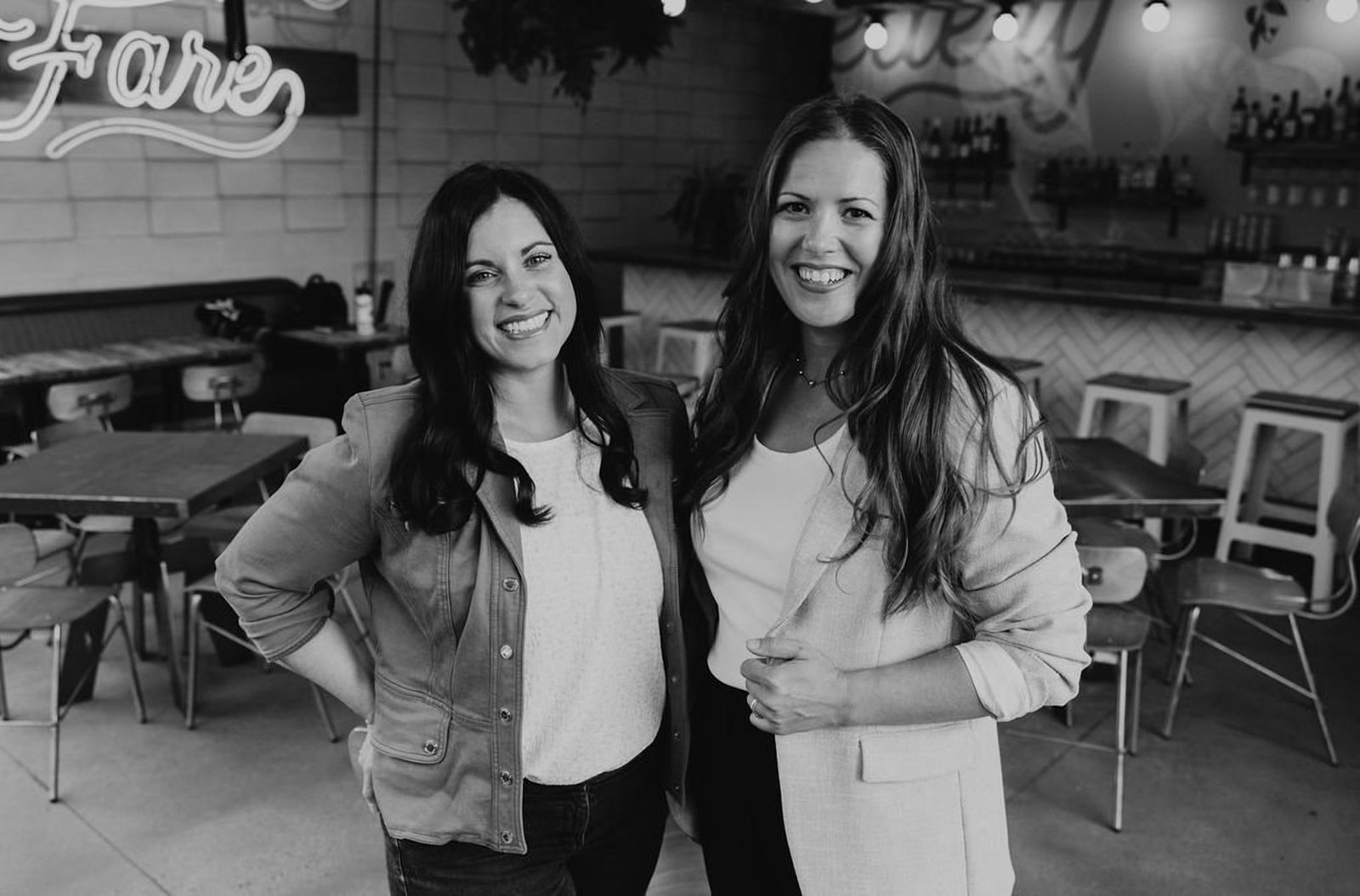 Black and white photograph of Keri and Erin standing together in the restaurant where The Collective began