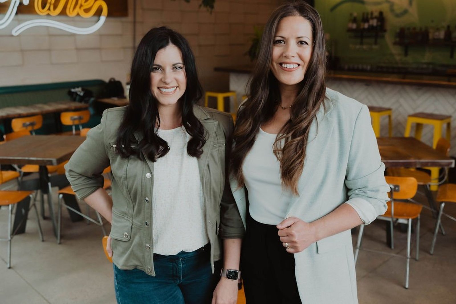 Keri Hinterreiter and Erin Hildmann, co-founders of The Collective for Designers, standing together in a Denver restaurant